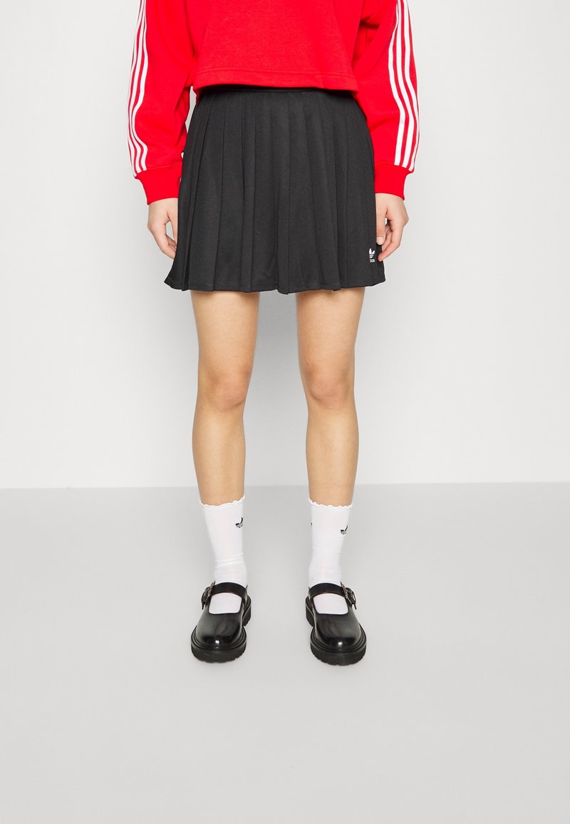 Czarna plisowana spódnica, zestawiona z białymi skarpetkami z falbankami i czarnymi butami Mary Jane. Strój składa się z czerwonego swetra z trzema białymi paskami.