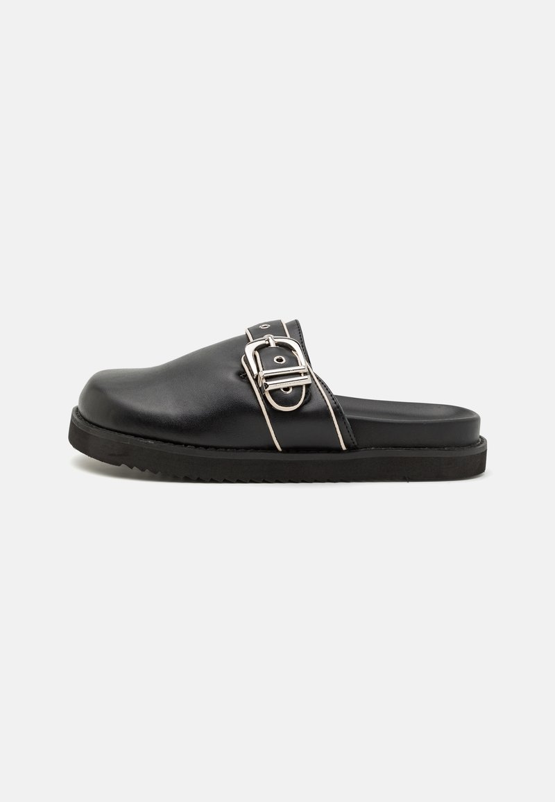 Mule noir à enfiler avec semelle épaisse, large boucle en métal argenté sur la lanière supérieure et bout rond fermé, présenté de côté gauche sur fond blanc.
