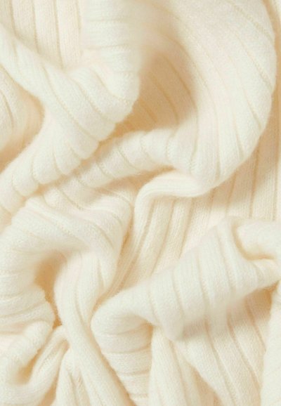 Tissu en maille côtelée blanc doux, avec des plis délicats et une texture, créant une apparence confortable et chaleureuse.