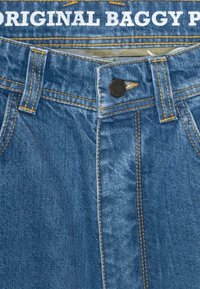 Denim jeans med en løs passform, med knaplukning, orange syninger og et hvidt mærke med teksten "ORIGINAL BAGGY P" ved taljen.