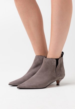Botas de tobillo de ante gris con puntera afilada, paneles laterales elásticos y un tacón pequeño. Textura suave y diseño minimalista.