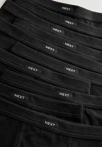 Čierne pánske spodné prádlo s elastickými páskami, prezentované s bielymi štítkami "NEXT". Viacero párov uložených na seba, zvýrazňujúcich mäkkú tkaninu a hladkú textúru.