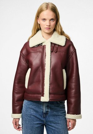 Giacca di pelle bordeaux con colletto e rifiniture in shearling crema, caratterizzata da un design squadrato, grandi tasche e dettagli in metallo.