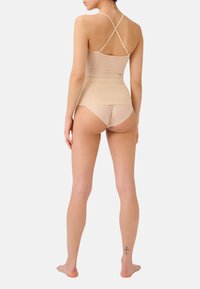 Naakt bodysuit met kruislingse bandjes, naadloos ontwerp en een gladde textuur; gecombineerd met bijpassende bikini briefs, beiden bieden een slanke silhouet.