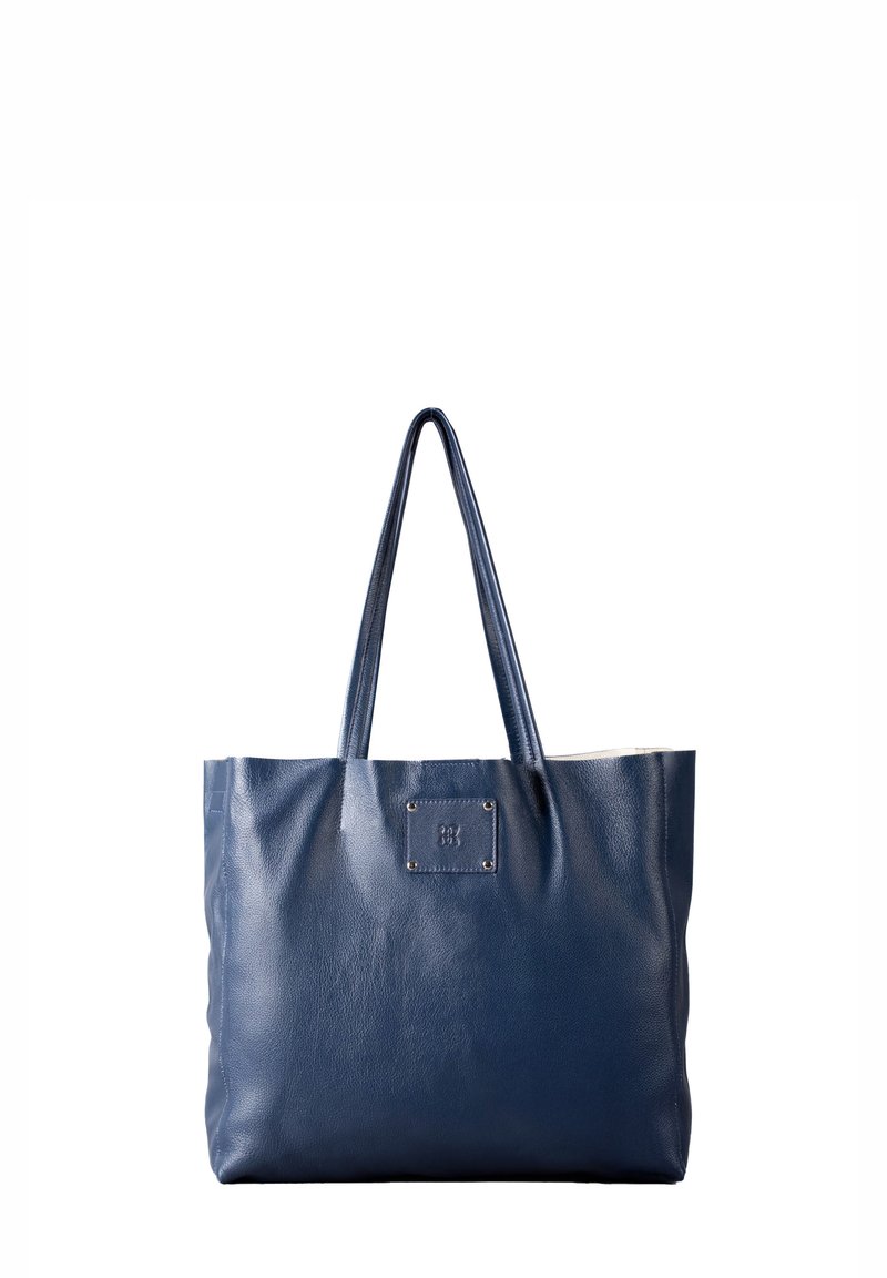 Navy blue leather tote bag with two handles, featuring a square logo patch and a textured finish. Open top and spacious interior.