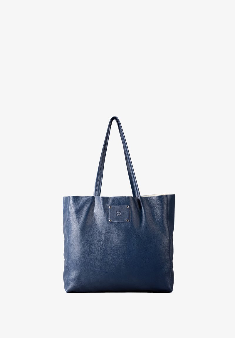 Navy blue leather tote bag with two handles, featuring a square logo patch and a textured finish. Open top and spacious interior.