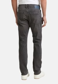 Gray denim jeans with a straight fit, featuring two back pockets and a leather patch on the waistband. Accompanied by white shoes.
