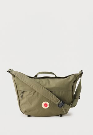 Olijfgroene boodschappentas met verstelbare schouderriem, bovenhandvat, voorvak met ritssluiting en een ronde rode en beige logopatch.