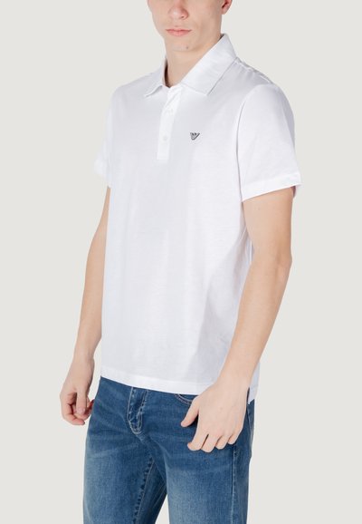 Polo en coton blanc avec un col classique, trois boutons et des manches courtes. Présente un petit logo noir sur la poitrine gauche.
