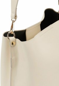 Borsa tote sintetica color crema con una superficie liscia, una clip in metallo dorato e un'apertura ampia sulla parte superiore per una facile accessibilità.