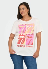 Hvid bomulds t-shirt med en grafisk print af fire farverige læber og teksten "rolling stones" i rød nederst. Kortærmet, afslappet pasform.