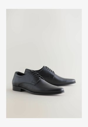 Schwarze Lederschuhe mit einer glatten und strukturierten Oberfläche, spitzem Zehenbereich, Schnürdesign und minimalistischer Niedrigabsatz.