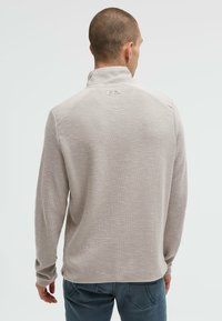 Hellgrauer Pullover mit strukturiertem Strickmuster, Reißverschlusskragen und einem kleinen Logoetikett auf der Rückseite. Lange Ärmel und lässige Passform.