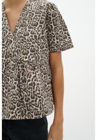 Top s leopardo vzorem s peplum střihem vyrobený z jemné látky, s hlubokým výstřihem do V, krátkými rukávy a nařaseným detailem v pase.
