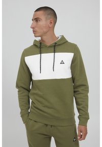 Felpa verde oliva con una striscia orizzontale bianca sul petto, cappuccio con cordini e piccolo logo triangolare sul lato sinistro.