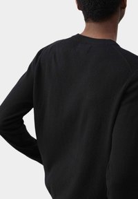 Maglione nero a maglia che mostra un primo piano del retro con un colletto rotondo, una texture sottile e maniche a raglan.