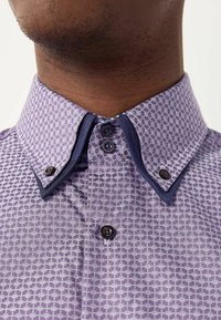 Paarse shirt met korte mouwen en een geometrisch patroon, voorzien van een marineblauwe contrastkraag en twee donkere knopen bij de hals.