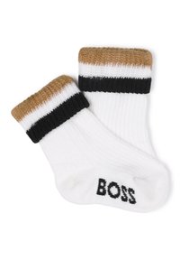 Calcetines de algodón blancos con un canalé texturizado, que presentan un puño a rayas en marrón y negro. "BOSS" está impreso en negro en la suela.