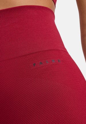 Close-up van rode getextureerde leggings met hoge taille, geribbelde tailleband en "FALKE"-logo aan de zijkant bij de heup.