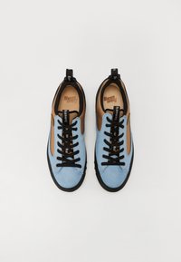 Adidași bleu deschis și bej cu șireturi negre, partea superioară din textil, talpă din cauciuc și design în două tonuri. Prezintă mici mânere pe călcâi și pe limbă.