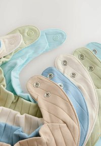 Sæt af stofproduktcovers i pastelfarver: lysegrøn, blå, creme og beige, med trykknapper og en ribbet tekstur.