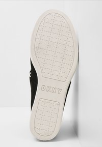 Baskets noires avec un dessus texturé et une semelle en caoutchouc blanc. Présente le logo 'DKNY' sur la semelle, avec une semelle à motif pour l'adhérence.