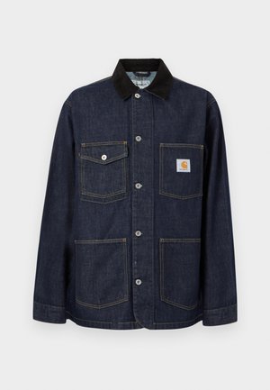 Tumši zila džinsa jaka ar melnu apkakli, četriem priekšējiem kabatām, tostarp viena ar Carhartt logotipa plāksteri, un pogu aizdari pa vidu.