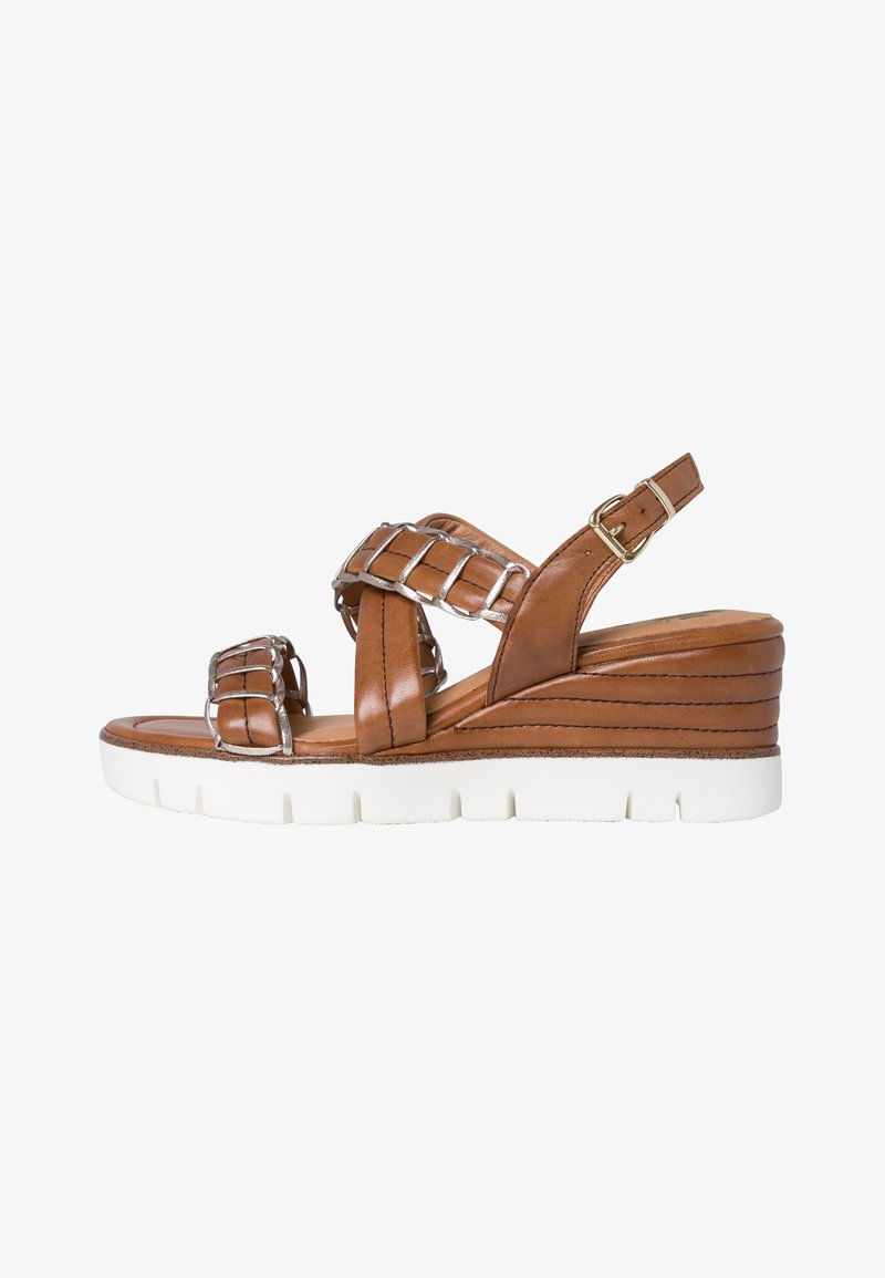 Brown leather wedge sandal with crisscross straps and silver accents. Textured upper and layered platform sole in white. Adjustable ankle strap.