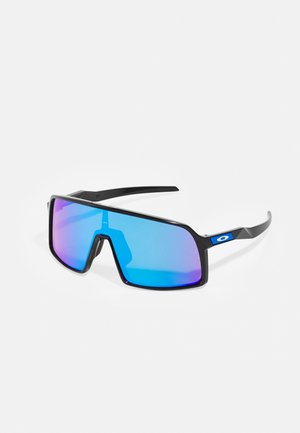 Des lunettes de soleil à monture noire avec de grandes verres angulaires dégradés de bleu à rose et un accent logo distinctif sur la branche.