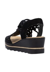 Sandale compensée noire avec un dessus en suède et un design découpé, semelle intérieure rembourrée beige et semelle extérieure texturée pour une meilleure adhérence.