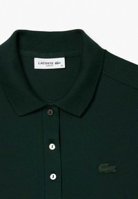 Polo shirt verde scuro realizzato in tessuto texture, con colletto, patta con tre bottoni e logo ricamato nello stesso colore.