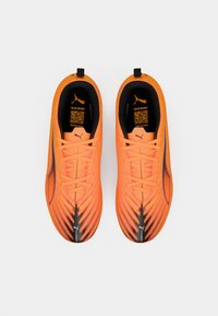 Scarpe da ginnastica di un vivace arancione con accenti neri. Parte superiore testurizzata, punta appuntita e lacci piatti. Dotate di un linguetta sul tallone.