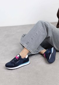 Zapatillas deportivas azul marino con cordones rosa, hechas de material de ante y malla, con una suela blanca y azul clara, que presenta una suela de goma texturizada.