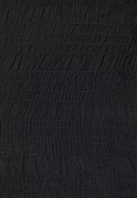 Tecido preto texturizado com pregas horizontais, apresentando um design enrugado e linhas de costura definidas, proporcionando uma aparência em camadas.