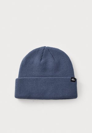 Knitted beanie in dark blue, featuring a folded cuff. Textured material with a small black brand logo tag on the side.