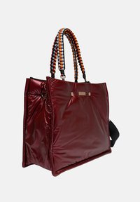 Rode glanzende tote bag met ingeweven gekleurde handvatten, met een rechthoekige vorm, metalen accenten en een ruime binnenkant.