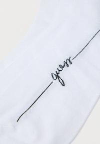 Chaussette en coton blanc présentant un texte brodé noir et un design à ligne fine, mettant en avant une texture lisse et un style simple et minimaliste.