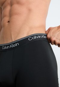 Boxeri negri din bumbac, cu o talie elastică moale, având un design neted și ajustat, decorate cu brandingul alb "Calvin Klein".