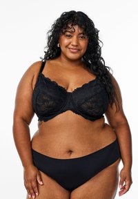 Black lace underwire bra with floral pattern, scalloped edges, and adjustable straps. Paired with seamless black bikini bottoms.