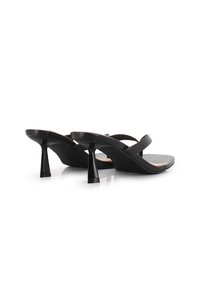 Sandalias de tacón negro con textura suave, que cuentan con tiras cruzadas y un tacón afilado. La suela es ligeramente acolchada y tiene un acabado mate.