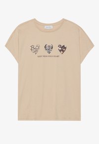 Beige T-shirt med korte ærmer, med tre hjerte designs i dyremønstre og teksten "BEVAR DIT VILLE HJERTE" nedenfor.