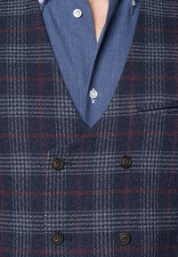 Granatowa kraciasta marynarka dwurzędowa z brązowymi guzikami, wykonana z teksturowanej mieszanki wełny, z koszulą chambray pod spodem.