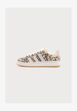 Χαμηλό sneaker με μπεζ και μαύρο λεοπάρ σχέδιο, λευκά κορδόνια, κρεμ ρίγες και λευκή σόλα σε ανοιχτό γκρι φόντο.