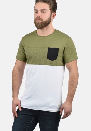 Majica kratkih rukava s maslinasto zelenim gornjim dijelom s mrljastom teksturom, crnom džepom i bijelim donjim dijelom, izrađena od pamučne tkanine.