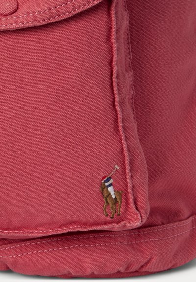 Κοντινό πλάνο κόκκινου υφάσματος με ραμμένο ραφτό και μικρό κεντημένο λογότυπο παίκτη πόλο πάνω σε άλογο που κρατάει μαλέτα.