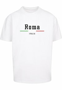 Hvit bomull t-skjorte med "Roma" i fet svart tekst, med grønne og røde horisontale linjer under, og "ITALIA" i mindre svart tekst.