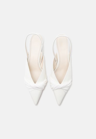 Ζευγάρι λευκά μυτερά παπούτσια slingback με στριφτή λεπτομέρεια μπροστά, εμφανιζόμενα από πάνω σε απλό φόντο.