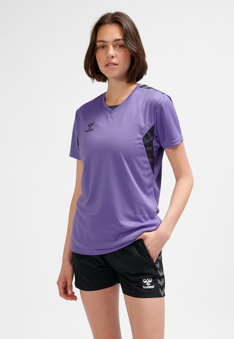 Lila atletisk t-shirt med korta ärmar och v-ringning. Svarta sidopaneler och hummerlogotyp på bröstet. Bärs med svarta shorts med ett mönster.