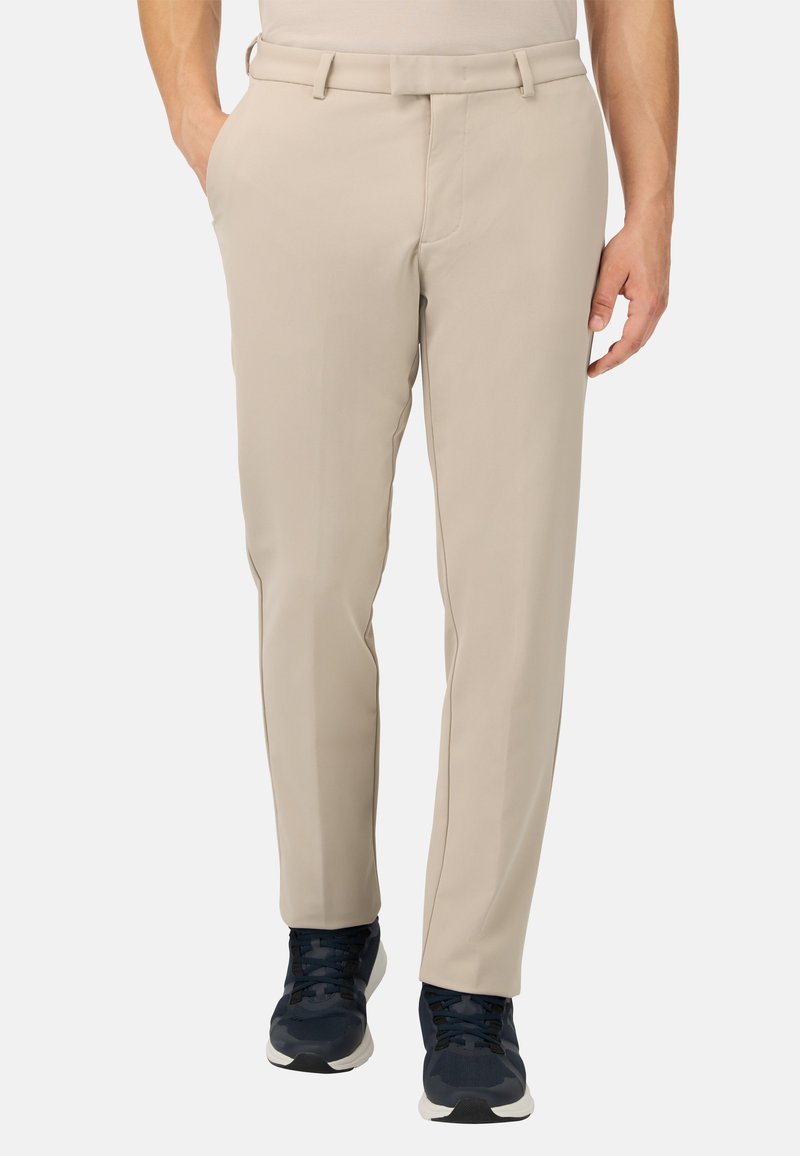 Beige dressbyxor i slätt tyg med rak front, bälteshällor och sidofickor. I kombination med svarta träningsskor.