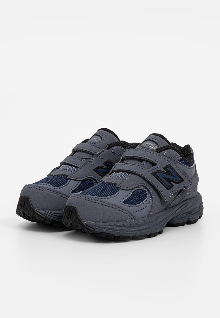Grijze sportieve schoenen met een mesh bovenwerk, zwarte accenten, dubbele klittenbandstraps en een getextureerde rubberen zool.